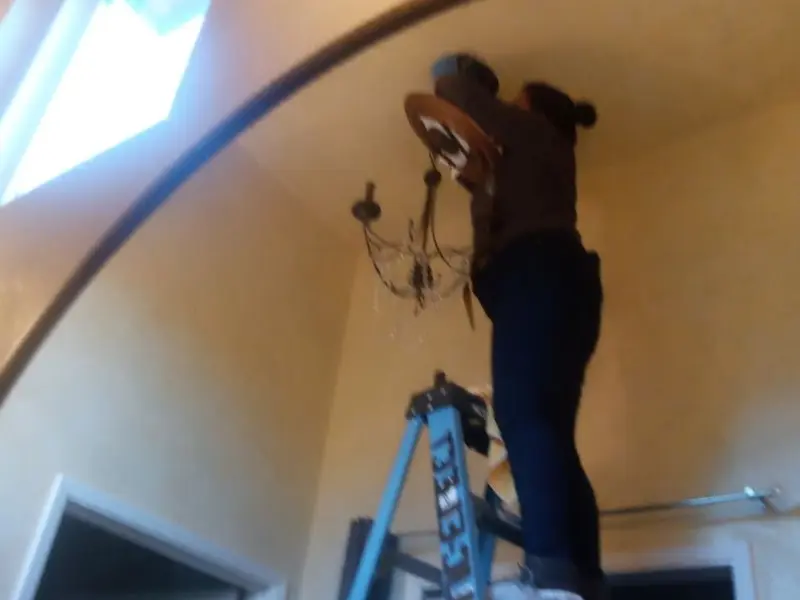 Electrician installing a chandelier in a South Run residence